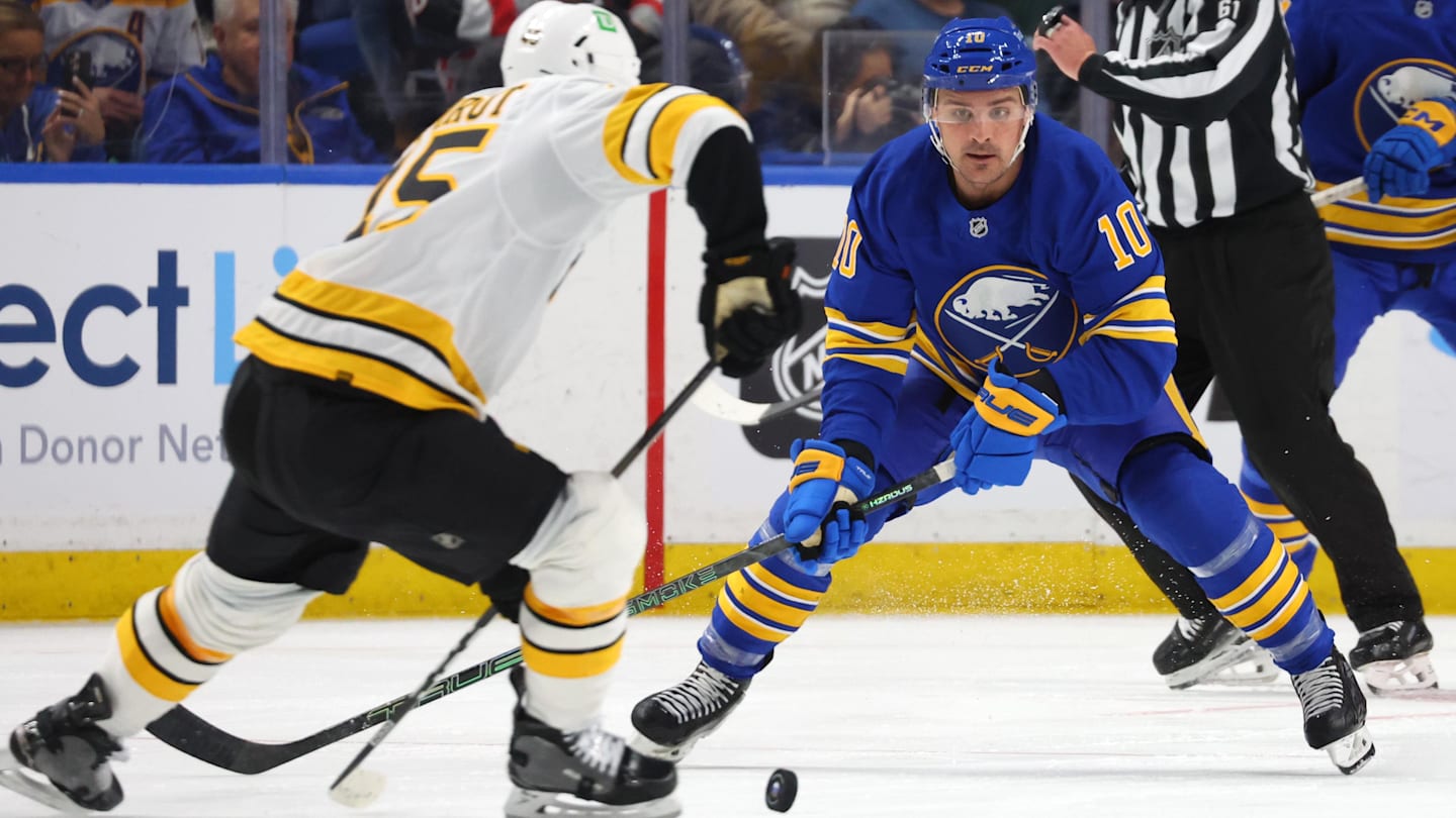 Mar 25, 2026; Buffalo, New York, USA;  Boston Bruins defenseman Jonathan Aspirot (45) makes a pass as Buffalo Sabres center Sam Carrick (10) defends during the second period at KeyBank Center. Mandatory Credit: Timothy T. Ludwig-Imagn Images