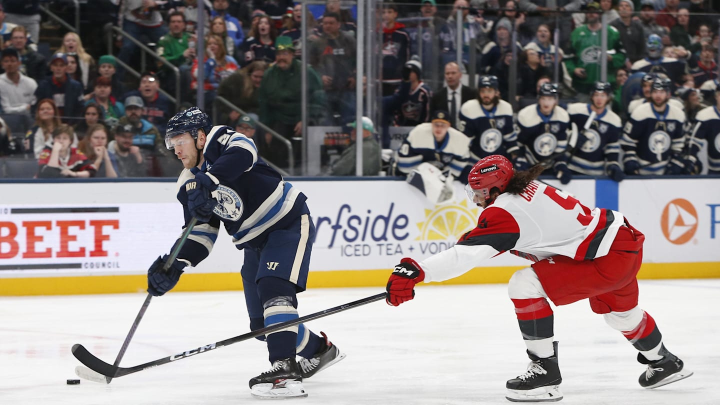 Mar 17, 2026; Columbus, Ohio, USA; Columbus Blue Jackets center Mathieu Olivier (24) wrists a shot on goal as Carolina Hurricanes defenseman Jalen Chatfield (5) defends during the second period at Nationwide Arena. Mandatory Credit: Russell LaBounty-Imagn Images