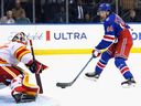 Dustin Wolf of the Calgary Flames defends the net against Gabe Perreault of the New York Rangers. 