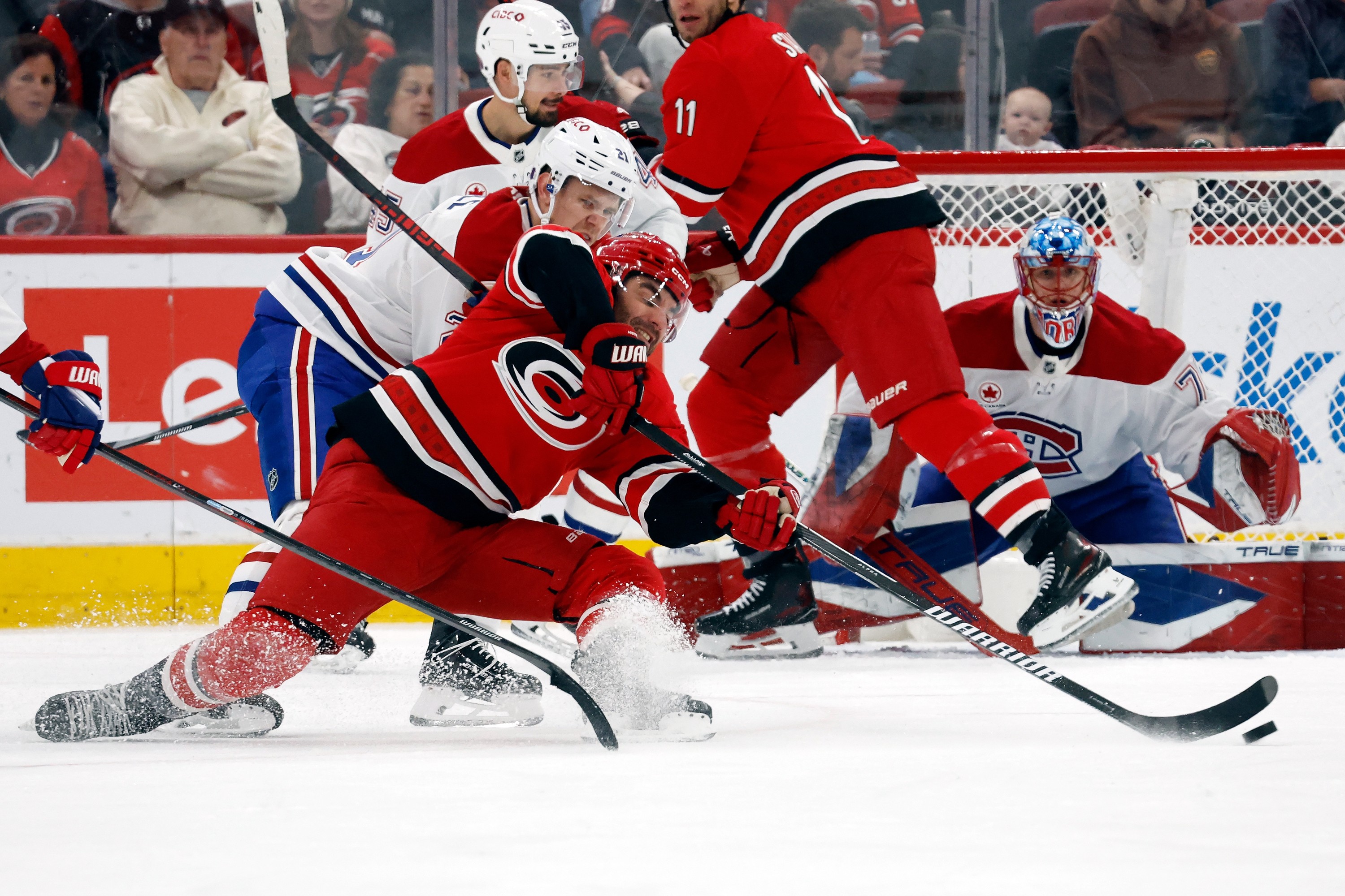 Carolina Hurricanes' Jordan Martinook is taken down by Montreal Canadiens' Kaiden Guhle.