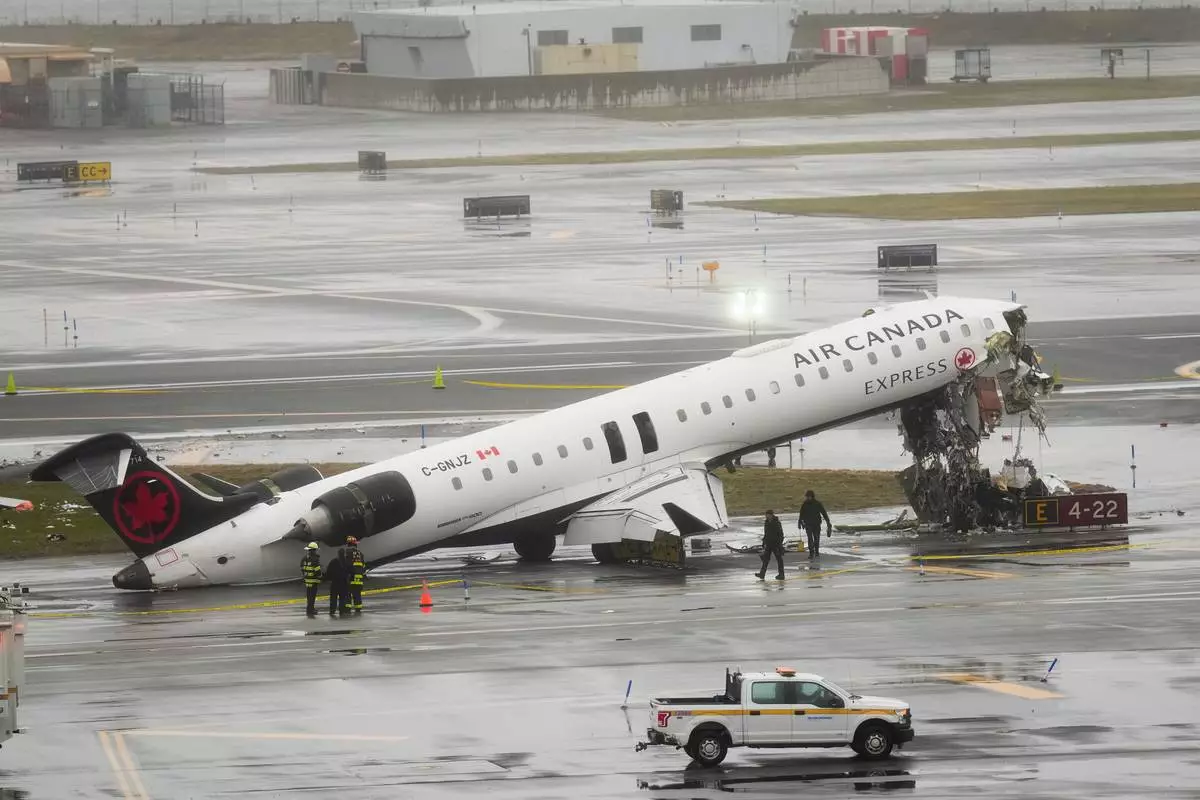 Firefighters and investigators examine the site, Monday, March 23, 2026, where an Air Canada jet came to rest after colliding with a Port Authority firetruck at LaGuardia Airport, after landing Sunday night in New York. (AP Photo/Seth Wenig)