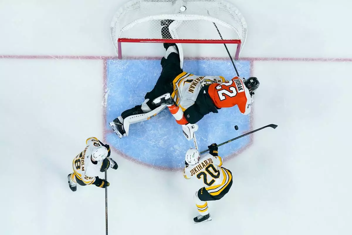 Boston Bruins' Jeremy Swayman, center left, makes a save on the shot attempt by Philadelphia Flyers' Christian Dvorak, right, during the second period of an NHL hockey game Saturday, Feb. 28, 2026, in Philadelphia. (AP Photo/Chris Szagola)