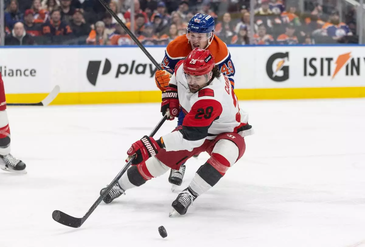 Carolina Hurricanes' William Carrier (28) and Edmonton Oilers' Ty Emberson (49) battle for the puck during second-period NHL hockey game action in Edmonton, Alberta, Friday March 6, 2026. (Jason Franson/The Canadian Press via AP)