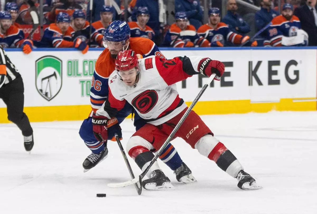 Carolina Hurricanes' Logan Stankoven (22) and Edmonton Oilers' Jake Walman (96) battle for the puck during third-period NHL hockey game action in Edmonton, Alberta, Friday March 6, 2026. (Jason Franson/The Canadian Press via AP)