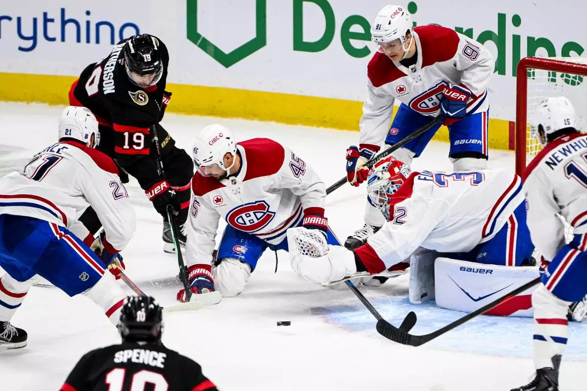 Montreal Canadiens goaltender Jacob Fowler (32) reaches out for the puck as Ottawa Senators' Drake Batherson (19) looks for a shot on goal opportunity during the third period of an NHL hockey game in Ottawa, Ontario, Wednesday, March 11, 2026. (Spencer Colby/The Canadian Press via AP)