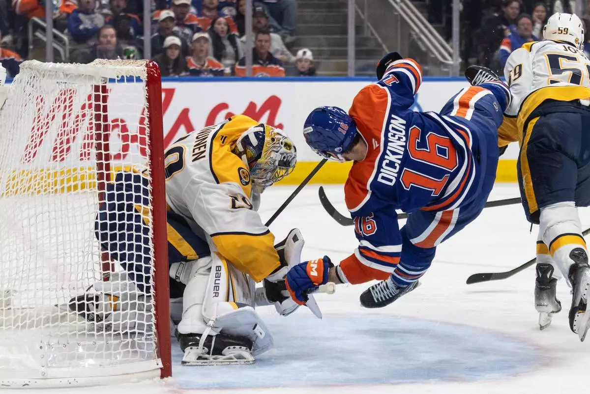 Nashville Predators goalie Justus Annunen (29) is crashed into by Edmonton Oilers' Jason Dickinson (16) during second period NHL action in Edmonton on Sunday, March 15, 2026. (Jason Franson/The Canadian Press via AP)