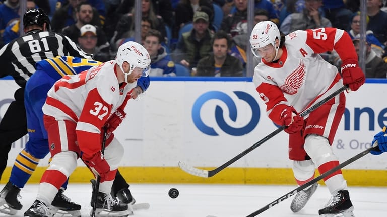 Detroit Red Wings defenseman Moritz Seider, right, clears the puck...