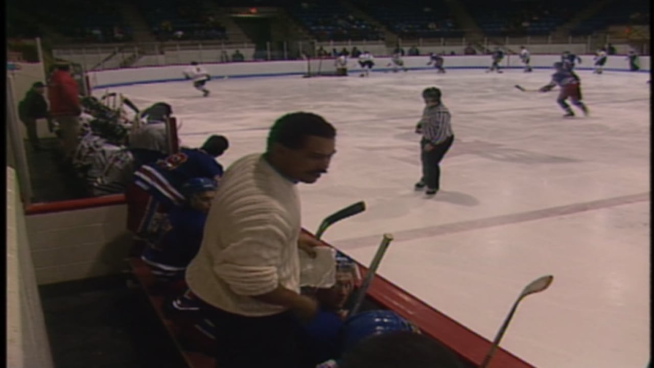 a man stands on the bench while a hockey game is played