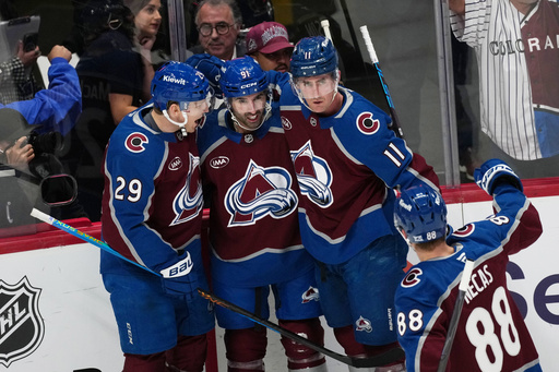 Colorado Avalanche center Nazem Kadri, center, is congratulated after scoirng a power play goal by center Nathan MacKinnon, left, and center Brock Nelson, right, as Colorado Avalanche center Martin Necas, front, joins in in the first period of an NHL hockey game against the Calgary Flames, Monday, March 30, 2026, in Denver. (AP Photo/David Zalubowski)