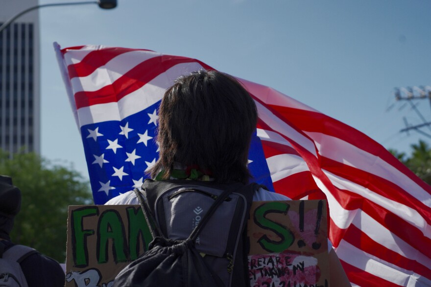 A woman holds an upside down American flag at the of the nationwide “No Kings” protest near the Lloyd George Courthouse, on Saturday, June 14, 2025, in Las Vegas.