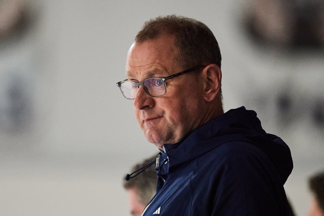 A man stands watching a hockey practice.