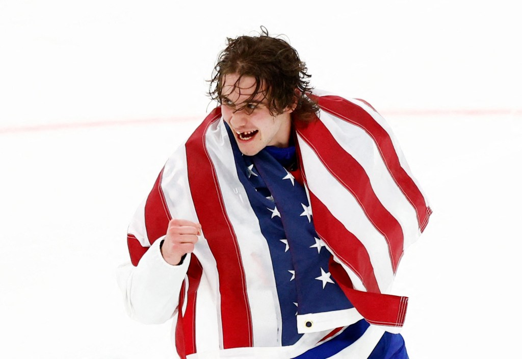 Jack Hughes celebrates draped in the American flag after winning gold.
