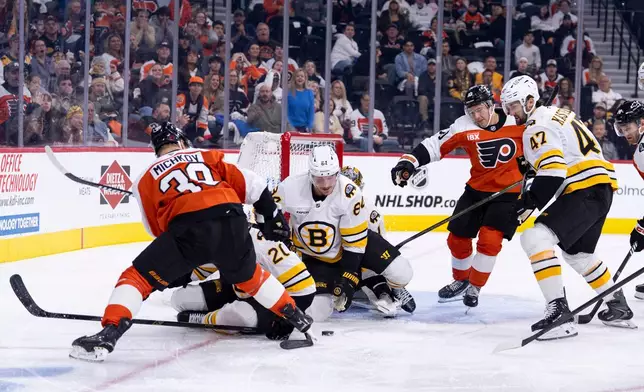 Boston Bruins' Tanner Jeannot, center, tries to clear the puck during the second period of an NHL hockey game Saturday, Feb. 28, 2026, in Philadelphia. (AP Photo/Chris Szagola)