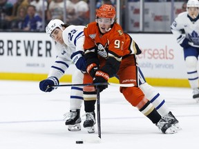 Leo Carlsson #91 of the Anaheim Ducks skates with the puck against Matthew Knies