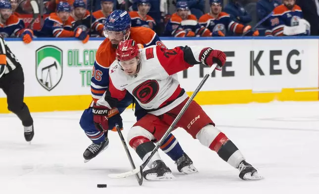 Carolina Hurricanes' Logan Stankoven (22) and Edmonton Oilers' Jake Walman (96) battle for the puck during third-period NHL hockey game action in Edmonton, Alberta, Friday March 6, 2026. (Jason Franson/The Canadian Press via AP)