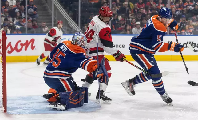 Carolina Hurricanes' Seth Jarvis (24) and Edmonton Oilers' Connor Murphy (5) battle as Oilers goalie Tristan Jarry (35) makes a save during first-period NHL hockey game action in Edmonton, Alberta, Friday March 6, 2026. (Jason Franson/The Canadian Press via AP)