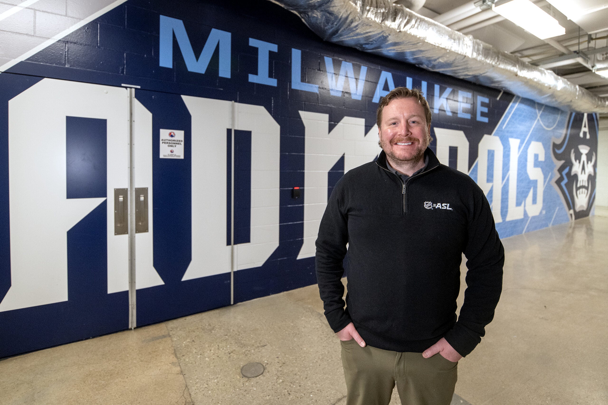 A man standing in front of a wall with blue letters.