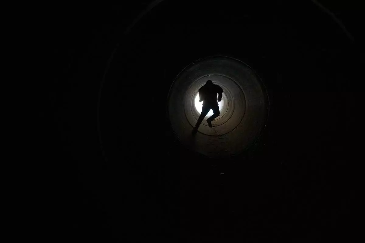 A boy runs inside cement pipe turned into a bomb shelter as air raid sirens warn of incoming Iranian missile strike in Michmoret, Israel, Tuesday, March 10, 2026. (AP Photo/Ariel Schalit)