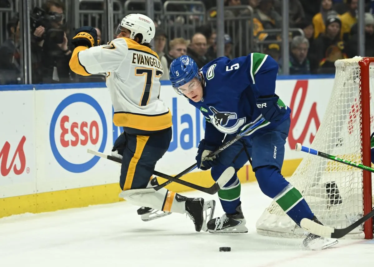 Vancouver Canucks defenseman Tom Willander (5) checks Nashville Predators right wing Luke Evangelista (77) during the first period at Rogers Arena.