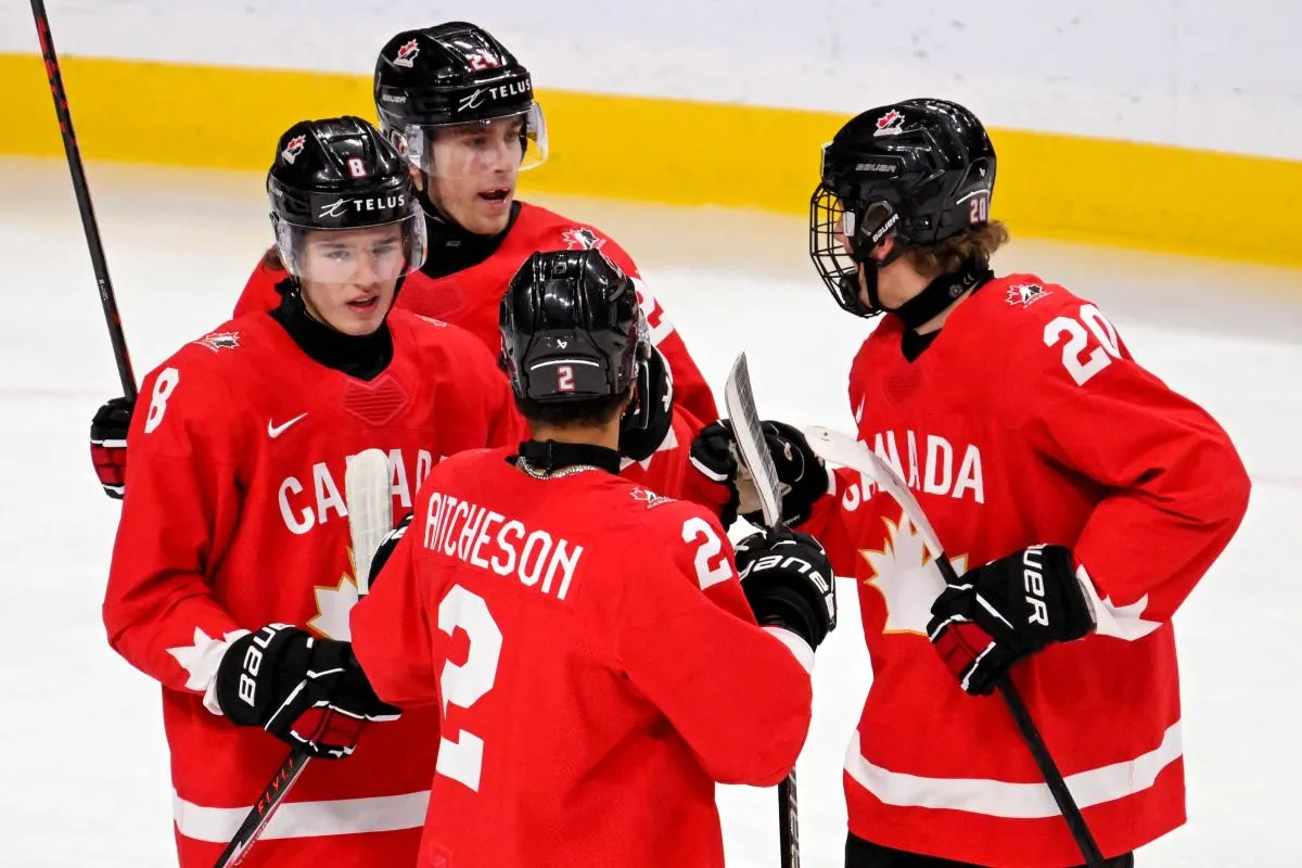 Canada forward Braeden Cootes (8) celebrates his goal against Finland with forward Liam Greentree (24), defensemen Kashawn Aitcheson (2), and defensemen Keaton Verhoeff (20) during the first period in the third place game of the 2026 IIHF World Junior Championship ice hockey tournament at Grand Casino Arena.