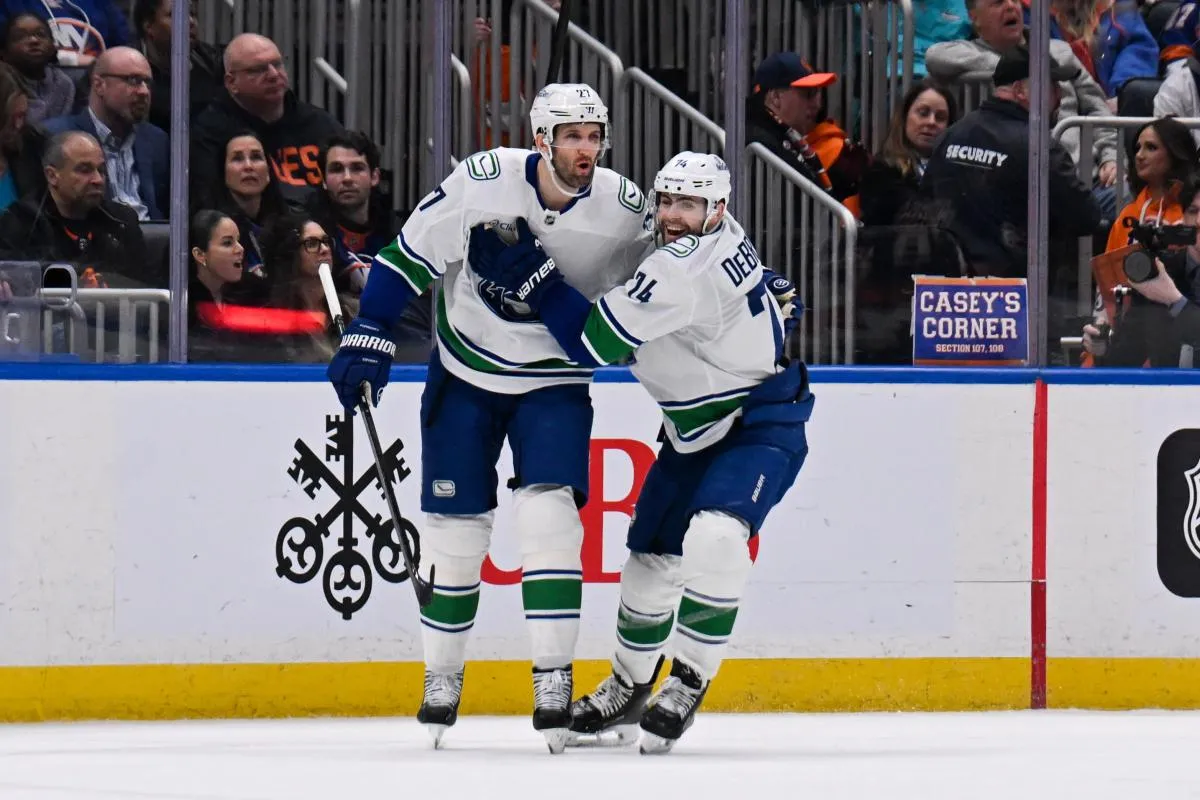 Vancouver Canucks defenseman Derek Forbort (27) celebrates his goal with left wing Jake DeBrusk (74) against the New York Islanders during the second period at UBS Arena.