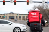 A food delivery motorcycle rider waits for the traffic light to change March 30, 2020, in...