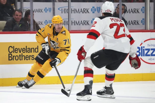 Feb 26, 2026; Pittsburgh, Pennsylvania, USA; Pittsburgh Penguins center Evgeni Malkin (71) skates with the puck against New Jersey Devils defenseman Brett Pesce (22) during the first period at PPG Paints Arena.