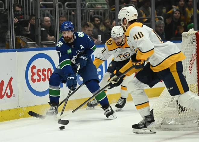 Mar 12, 2026; Vancouver, British Columbia, CAN; Vancouver Canucks defenseman Filip Hronek (17) controls the puck against Nashville Predators defenseman Nick Perbix (48) and defenseman Nicolas Hague (41) during the second period at Rogers Arena.