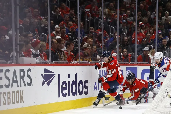Jan 4, 2025; Washington, District of Columbia, USA; Washington Capitals left wing Andrew Mangiapane (88) and New York Rangers defenseman Ryan Lindgren (55) battle for the puck in the third period at Capital One Arena.