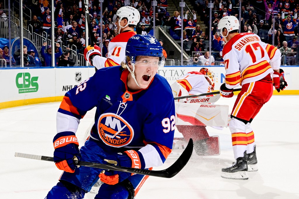 New York Islanders player Simon Holmstrom #92 celebrates after scoring his second goal against Calgary Flames player Devin Cooley #1.