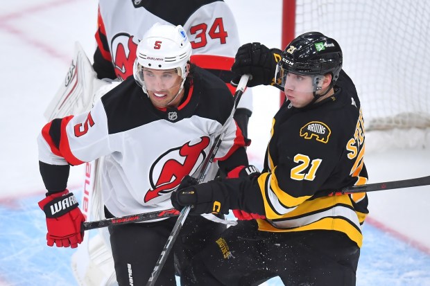 New Jersey Devils defenseman Brenden Dillon (5) and Boston Bruins center Alex Steeves (21) grapple for position in front of the net in the first period of an NHL game earlier this season. (AP Photo/Steven Senne)