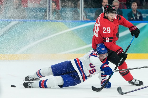 The United States' Quinn Hughes (43) and Canada's Nathan MacKinnon (29) battle for the puck during a men's ice hockey gold medal game between Canada and the United States at the 2026 Winter Olympics, in Milan, Italy, on Sunday, Feb. 22, 2026. (AP Photo/Petr David Josek)