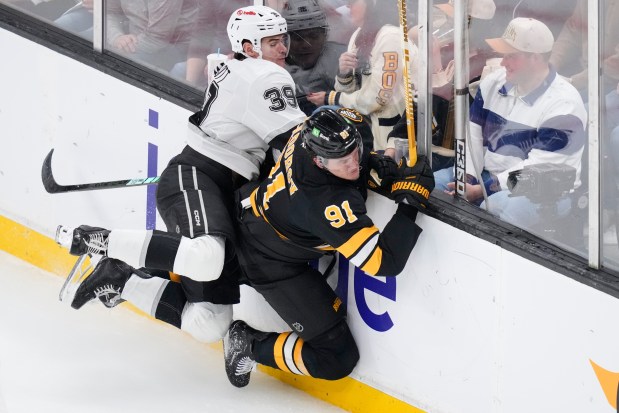 Boston Bruins defenseman Nikita Zadorov (91) is checked into the boards by Los Angeles Kings left wing Jeff Malott during the second period. (AP Photo/Charles Krupa)