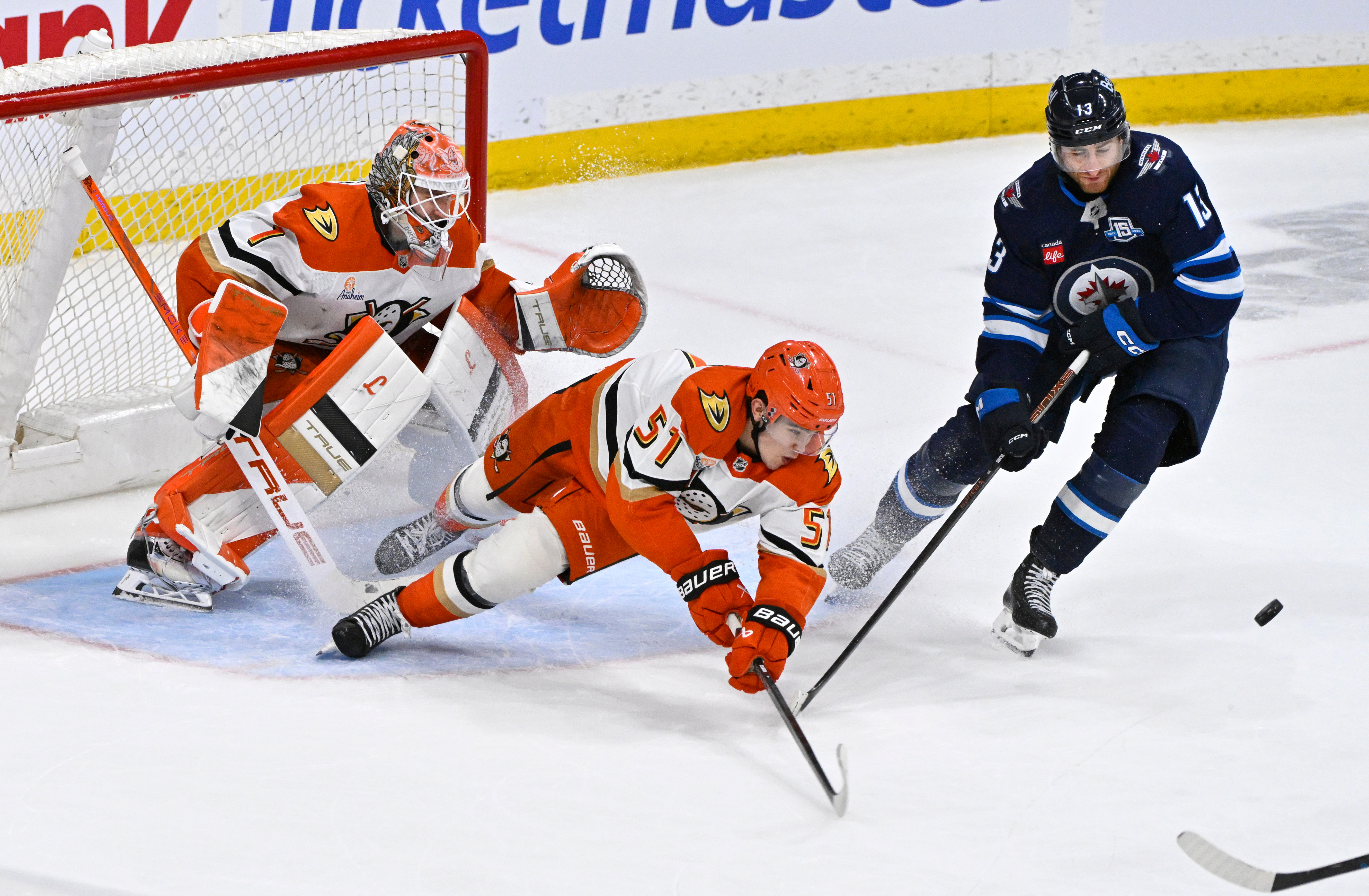 The Ducks’ Olen Zellweger, center, clears the puck from in...