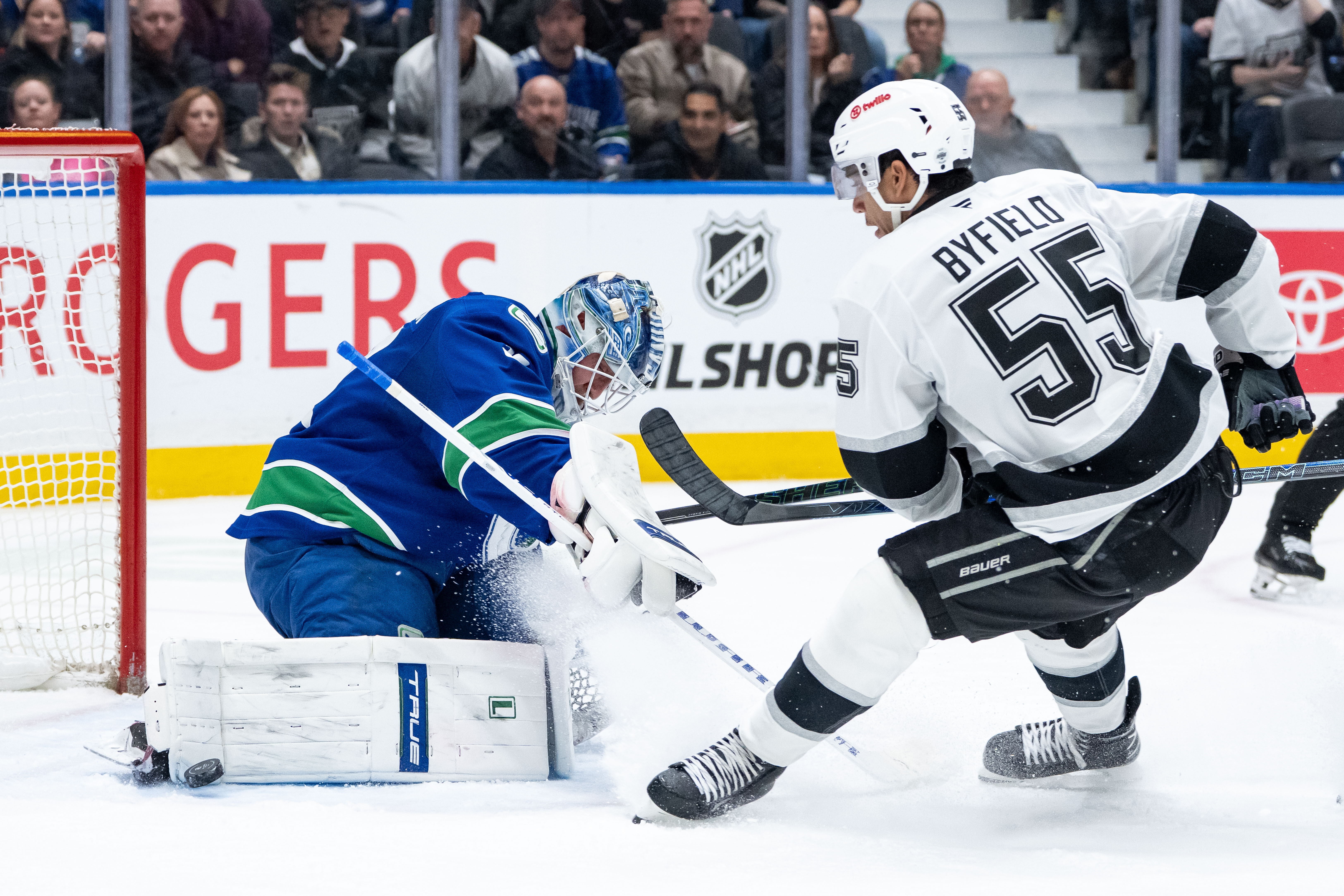 Vancouver Canucks goaltender Kevin Lankinen, left, stops a shot by...
