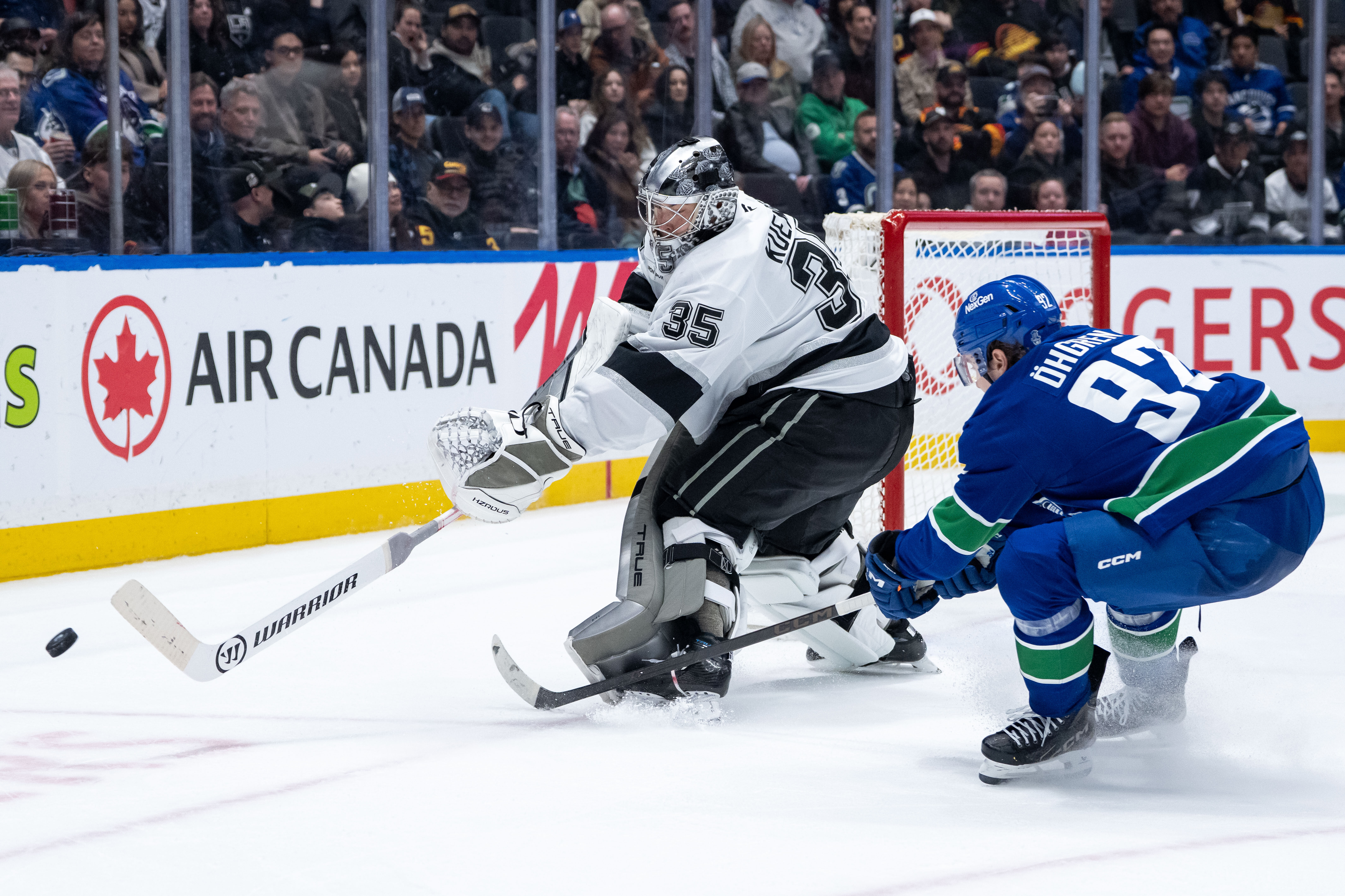 Kings goaltender Darcy Kuemper, left, dumps the puck as the...