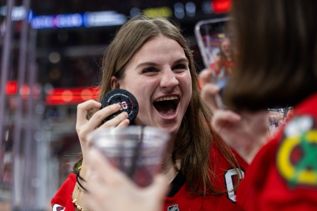 Caroline Ramsey, left of North Carolina reacts as she holds a puck while her friend Teresa Morozin, of Libertyville takes a photo of her in the first period of a game between the Chicago Blackhawks and the Utah Mammoth on Monday, March, 9, 2026, at the United Center. (Josh Boland/Chicago Tribune)