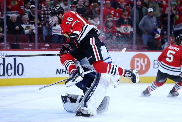 Chicago Blackhawks center Jason Dickinson (16) collides with Winnipeg Jets goaltender Connor Hellebuyck (37) in the third period of a game at the United Center in Chicago on Jan. 19, 2026. (Chris Sweda/Chicago Tribune)