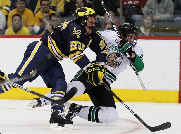 Brock Nelson of the North Dakota Fighting Sioux is hit by Luke Glendening of the Michigan Wolverines  during the semifinals of the 2011 NCAA Men's Frozen Four on April 7, 2011 at the Xcel Energy Center in St. Paul, Minnesota.  (Photo by Elsa/Getty Images)