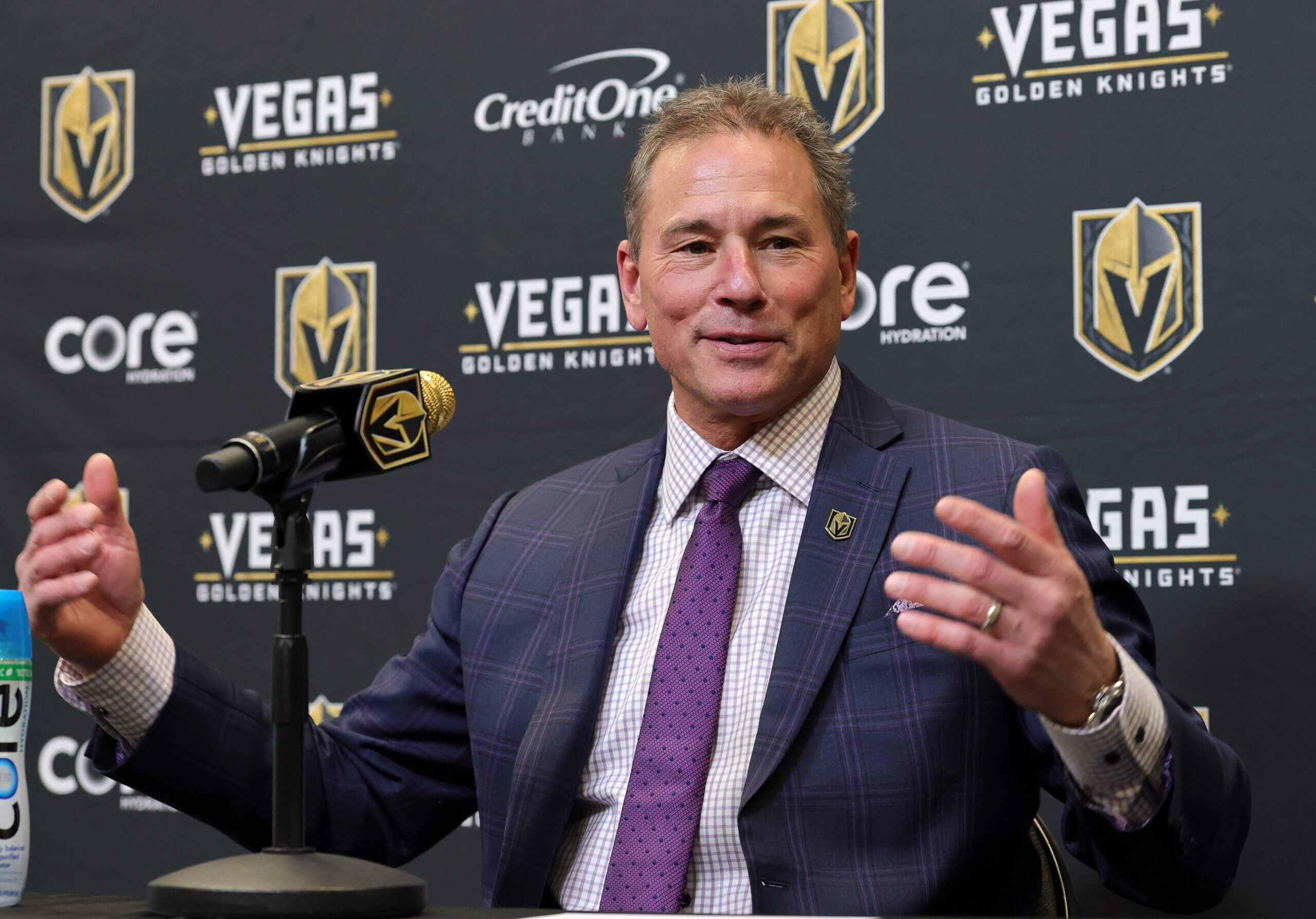 Bruce Cassidy answers questions during a news conference in front of a Golden Knights backdrop.