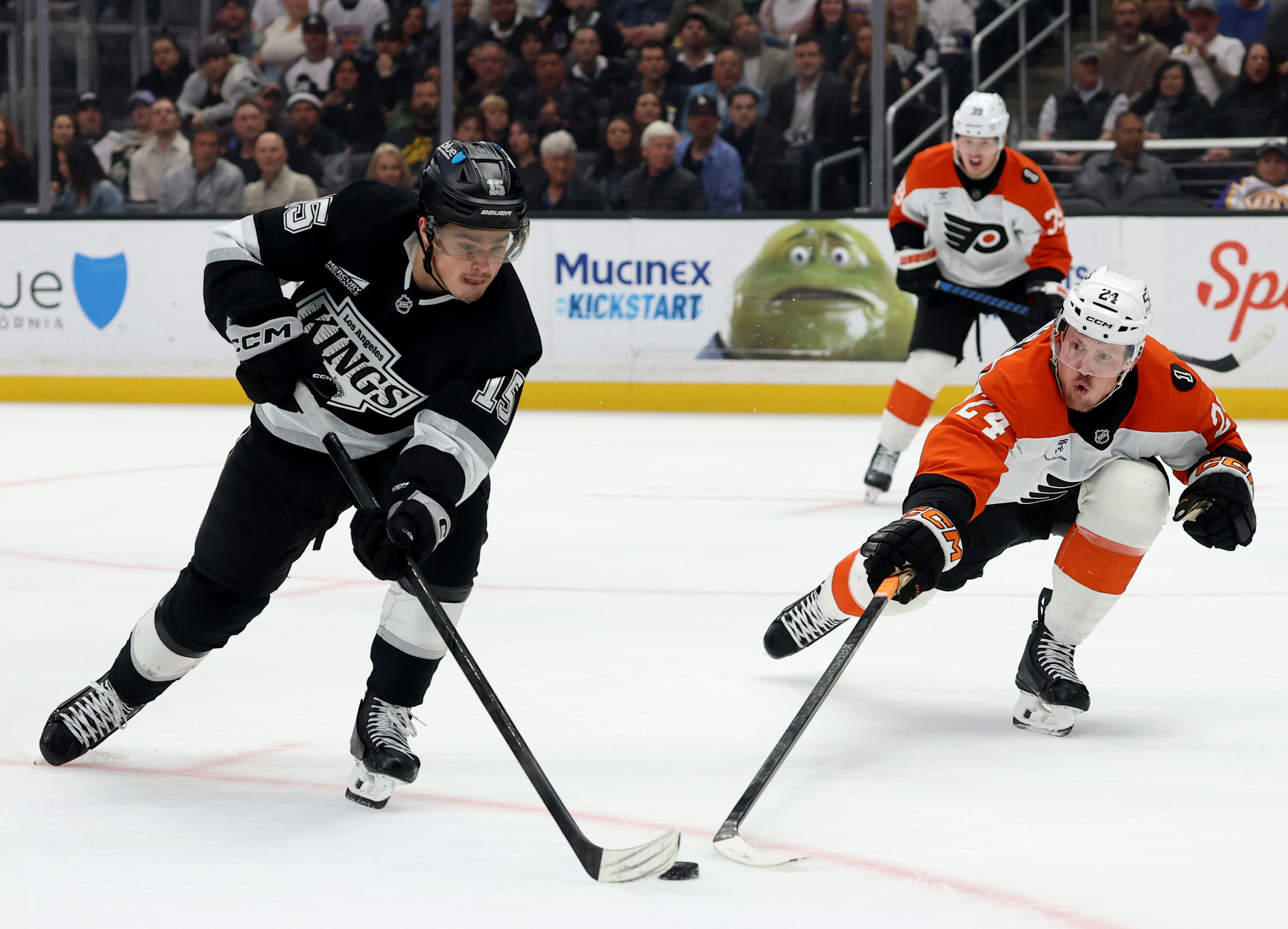 The Kings’ Alex Turcotte, left, plays the puck away from...