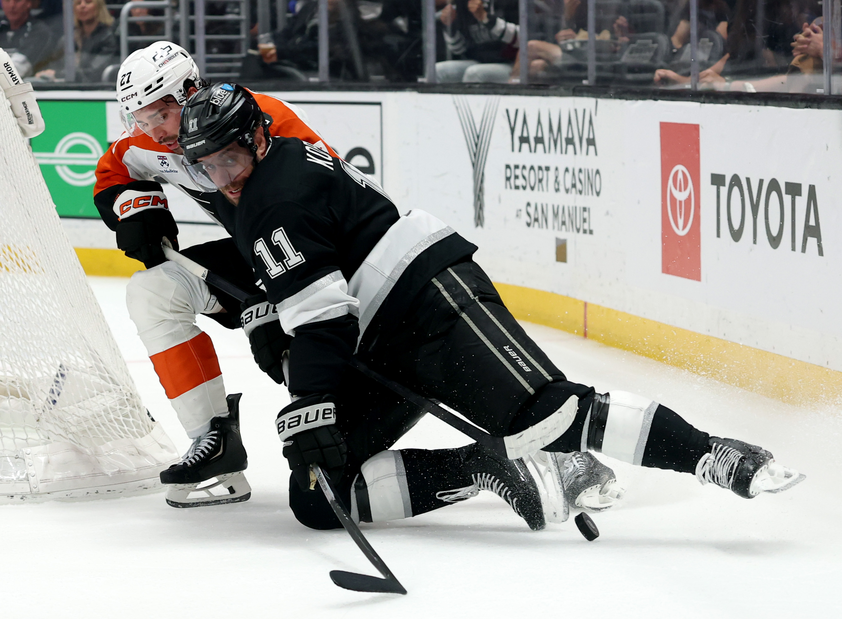 Kings captain Anze Kopitar, front, is tripped by the Philadelphia...