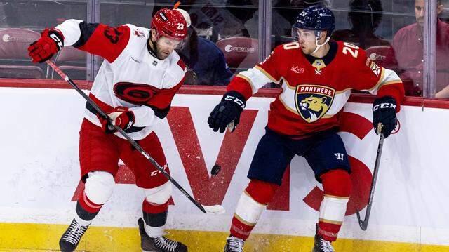 Florida Panthers defenseman Mike Benning (20) and Carolina Hurricanes left wing Josiah Slavin (23) fight for possession during the first period of an NHL game at Amerant Bank Arena on Monday, September 29, 2025, in Sunrise, Fla.