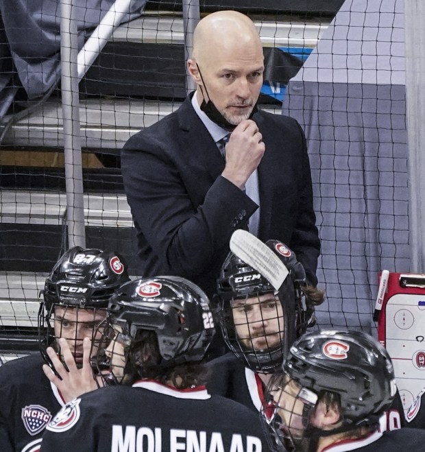 St. Cloud State head coach Brett Larson, top, talks with the team during the first period of the NCAA men's Frozen Four hockey championship game against Massachusetts in Pittsburgh, Saturday, April 10, 2021. (AP Photo/Keith Srakocic)