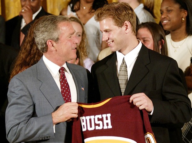 Then-President George W. Bush (L) receives a shirt from University of Minnesota's Grant Potulny (R) after a photo opportunity with the NCAA men's hockey champions in the East Room of the White House 17 June, 2003, in Washington, DC. (Photo by STEPHEN JAFFE/AFP via Getty Images)