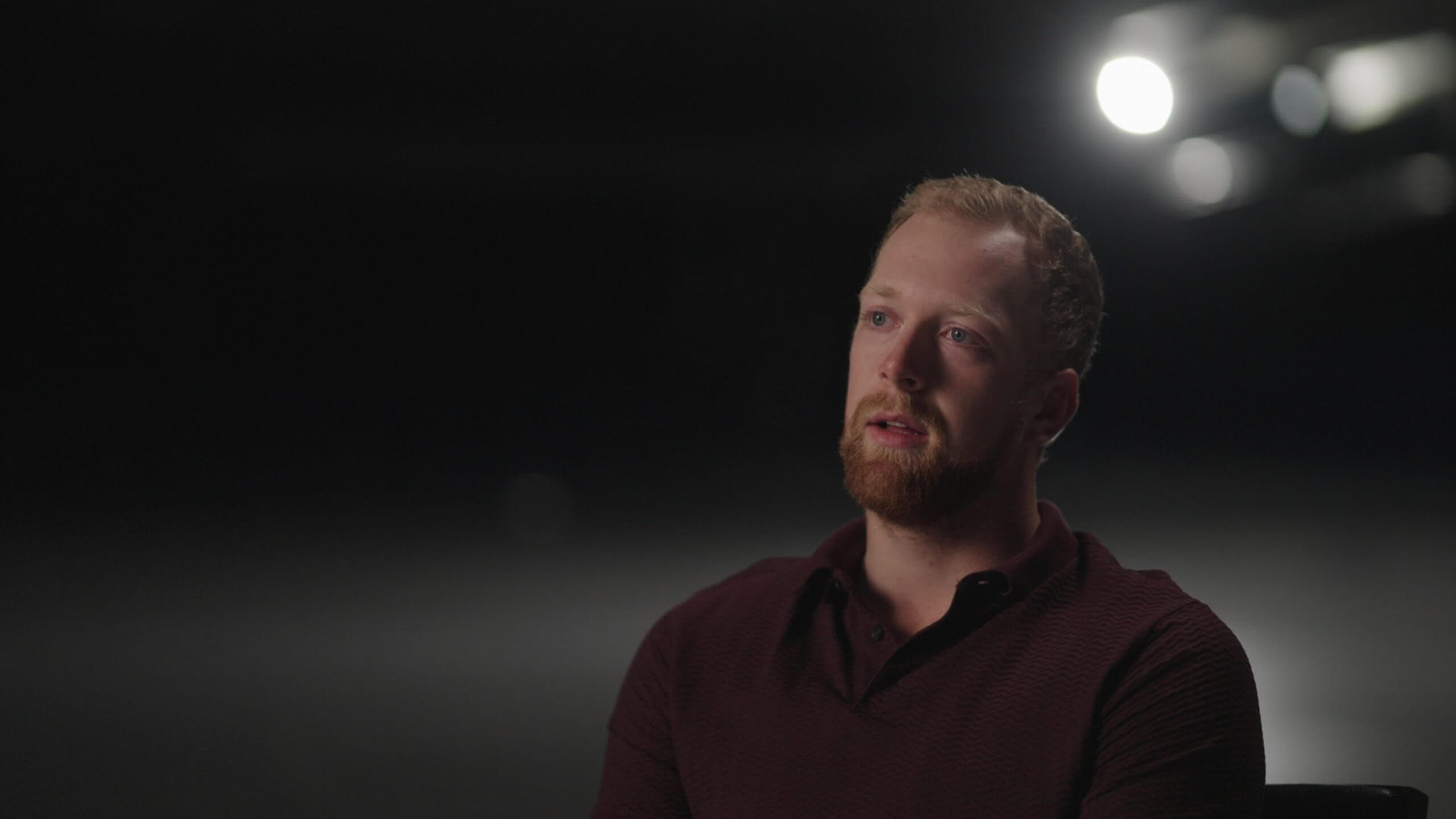 Luke Prokop, visible from chest up, sits in regular clothing in front of a dark background.