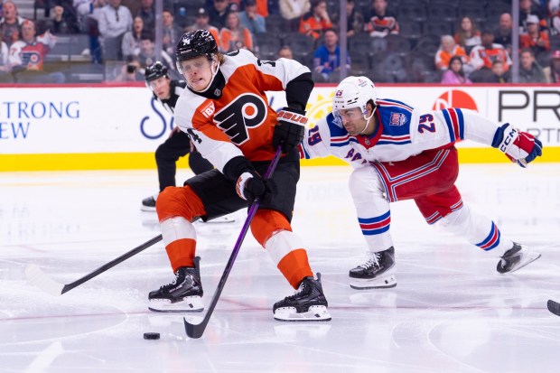 Philadelphia Flyers defenseman Nick Seeler, left, brings the puck into the zone with New York Rangers defenseman Matthew Robertson, right, trailing during the second period Monday, March 9, 2026, in Philadelphia. (AP Photo/Chris Szagola)
