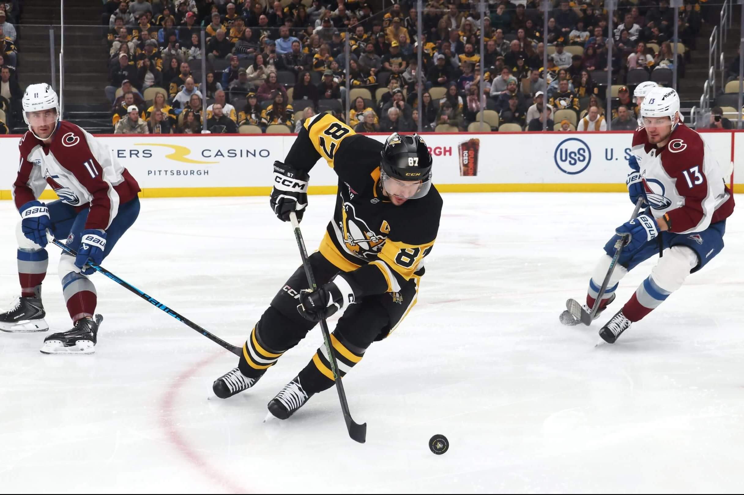 Pittsburgh Penguins captain Sidney Crosby moves the puck against Colorado Avalanche center Brock Nelson and right wing Valeri Nichushkin.