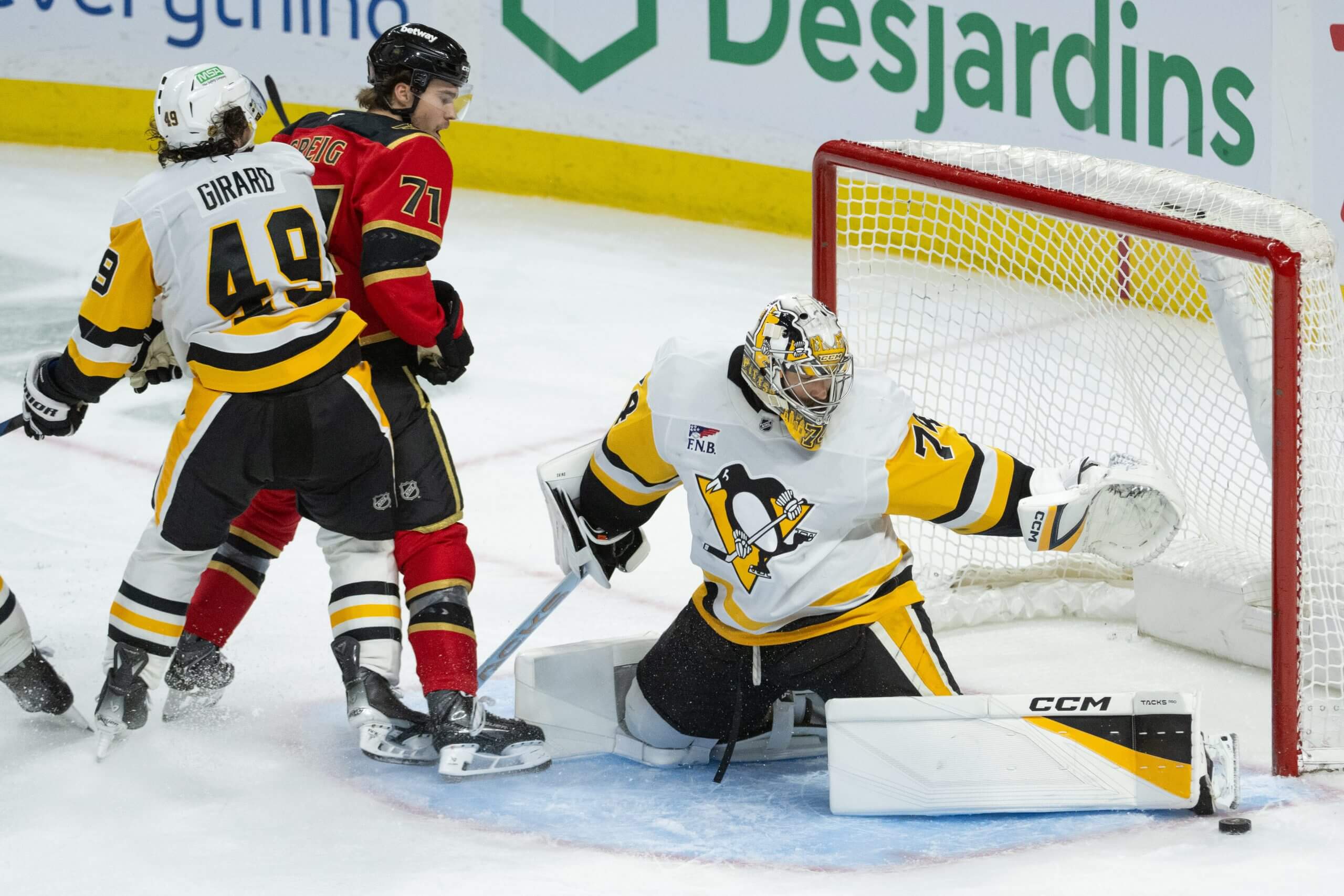 Stuart Skinner makes a leg pad save with Ottawa's Ridly Grieg and Pittsburgh's Sam Girard jostling in the corner of the crease.