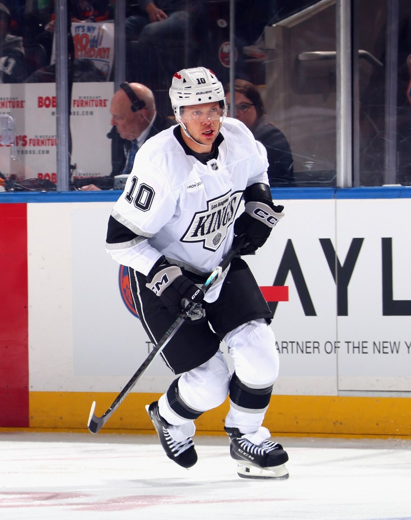 Artemi Panarin, wearing a white Los Angeles Kings jersey with "10" on the sleeve, skates on the ice with a hockey stick.